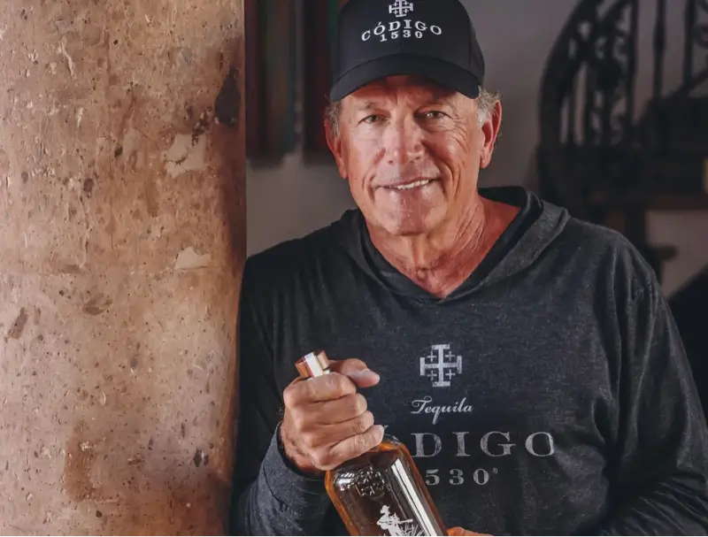 Mr George Strait holding a Codigo 1530 Rosa Bottle