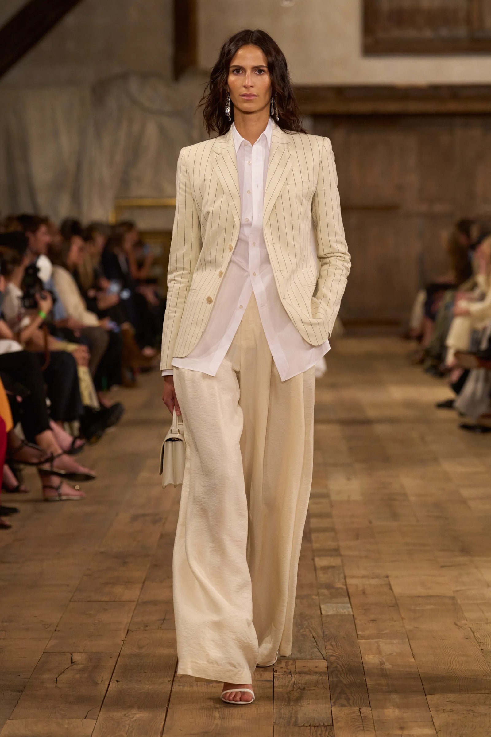 Modelo luce unos pantalones fluidos con pinzas blazer y sandalias de tiras en Ralph Lauren PrimaveraVerano 2024.