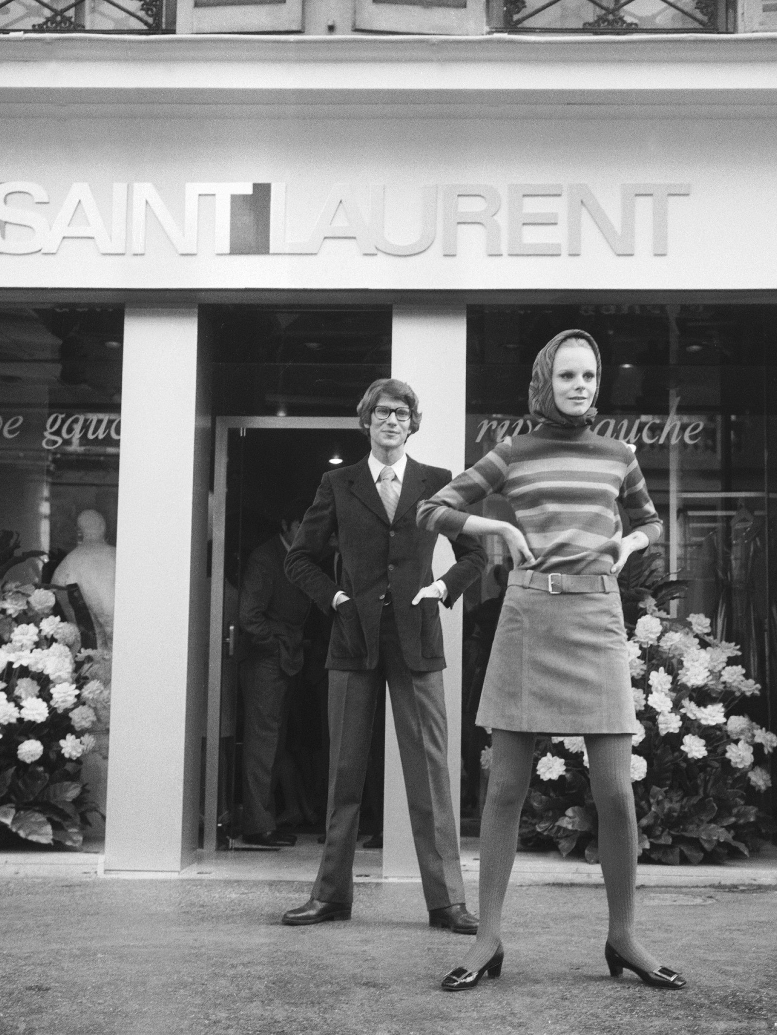 Image may contain Yves Saint Laurent Plant Potted Plant Adult Person Clothing Coat Flower and Flower Arrangement