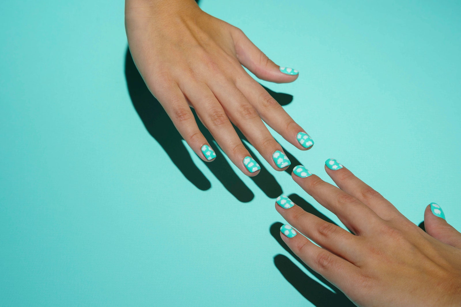 Two women's wellgroomed beautiful hands stretch towards each other. Beautiful female hands with colored manicure in...