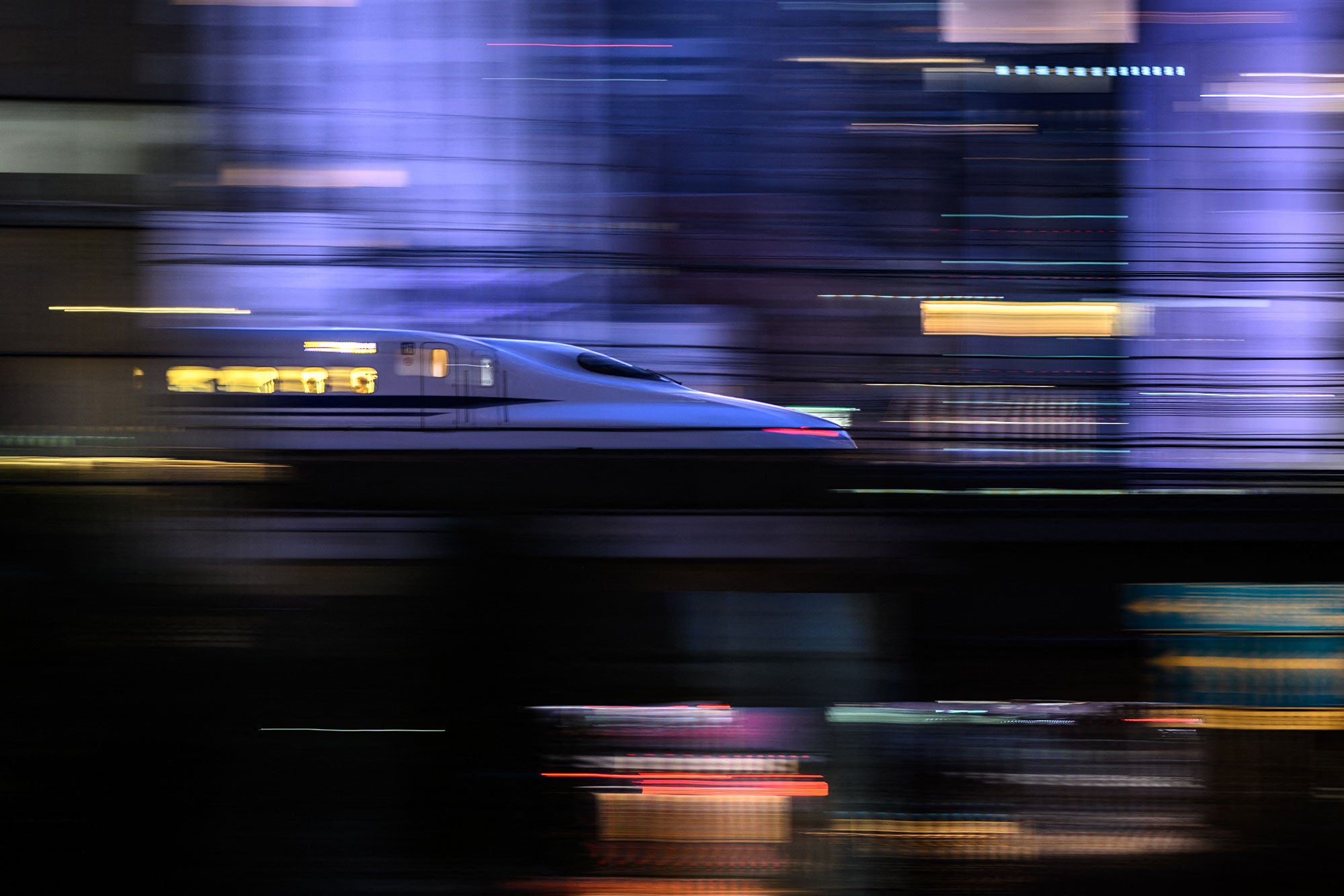 A blurred and lit-up high-speed train at twilight. 