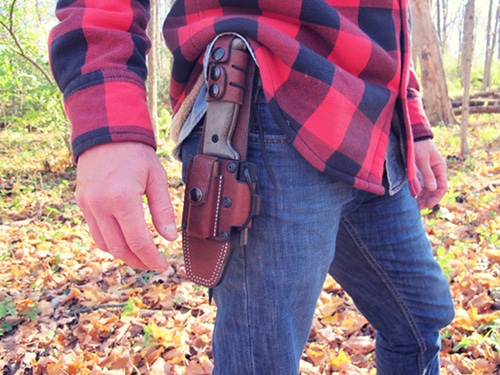Survival knife in leather holster on denim with red flannel.