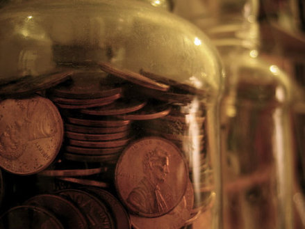 A frugally curated glass jar overflowing with a virtuous collection of coins.