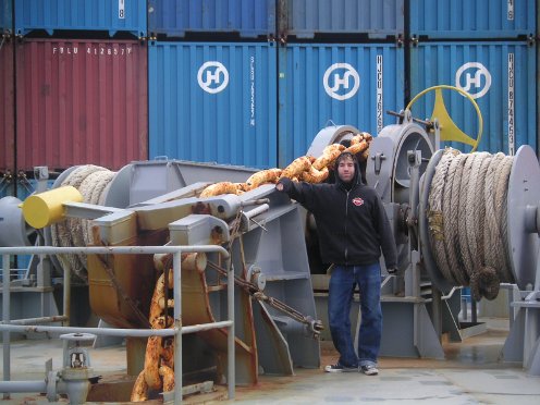 A man standing in front of a massive freighter ship.