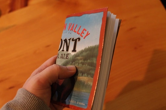 A person holding a book with a bear on a carton.