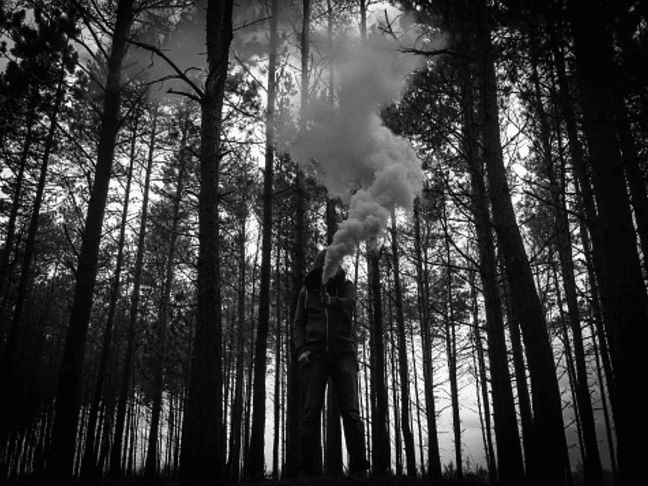 A quick snapshot of a person standing in the woods, captured in black and white.