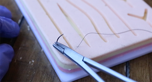 Passing thread through the cotton with needle holder. 