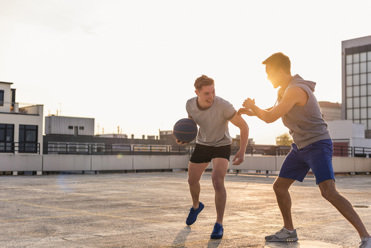 Two disappointed friends playing basketball on a rooftop.