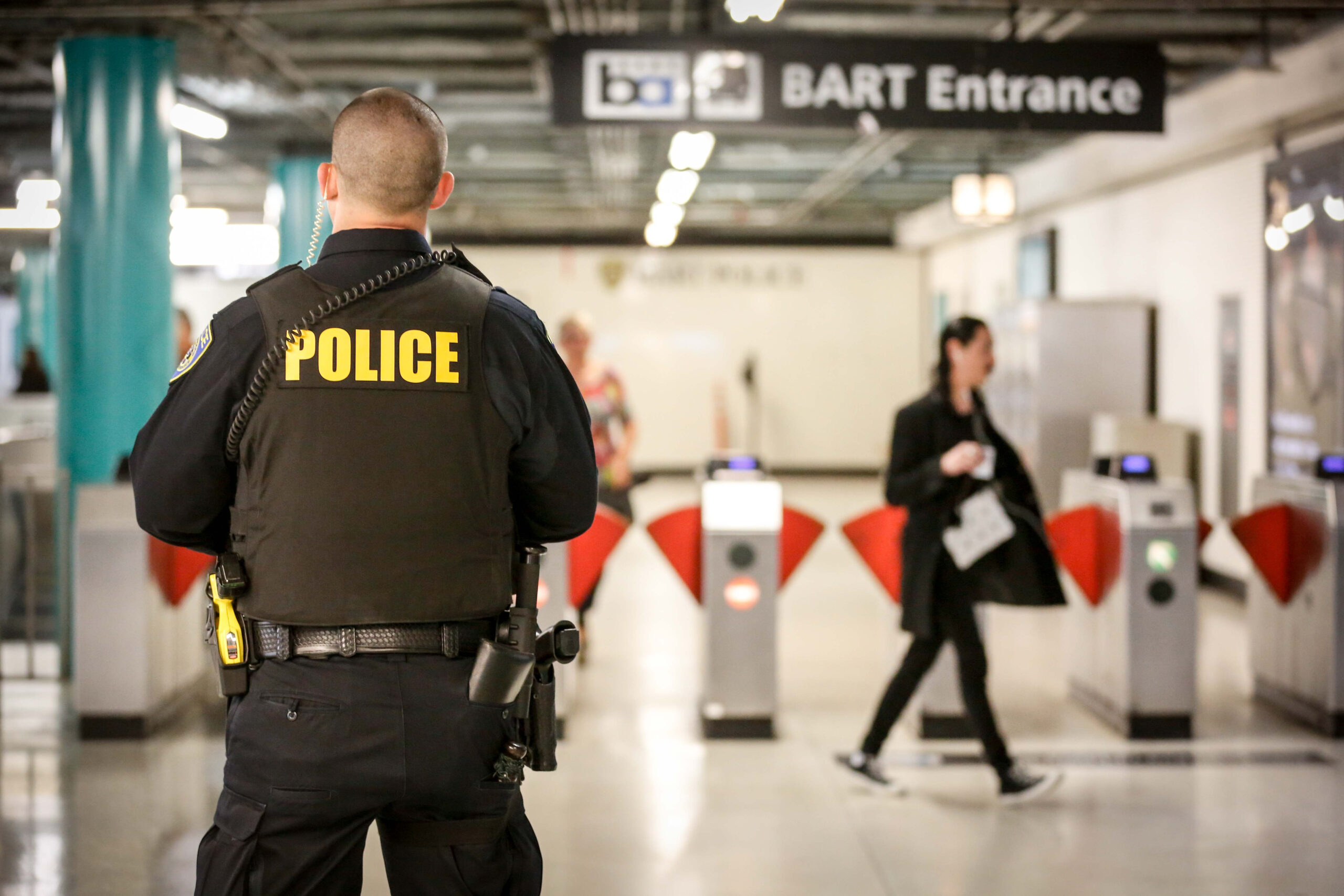 A police officer stands guard near the gates to enter the BART train system.