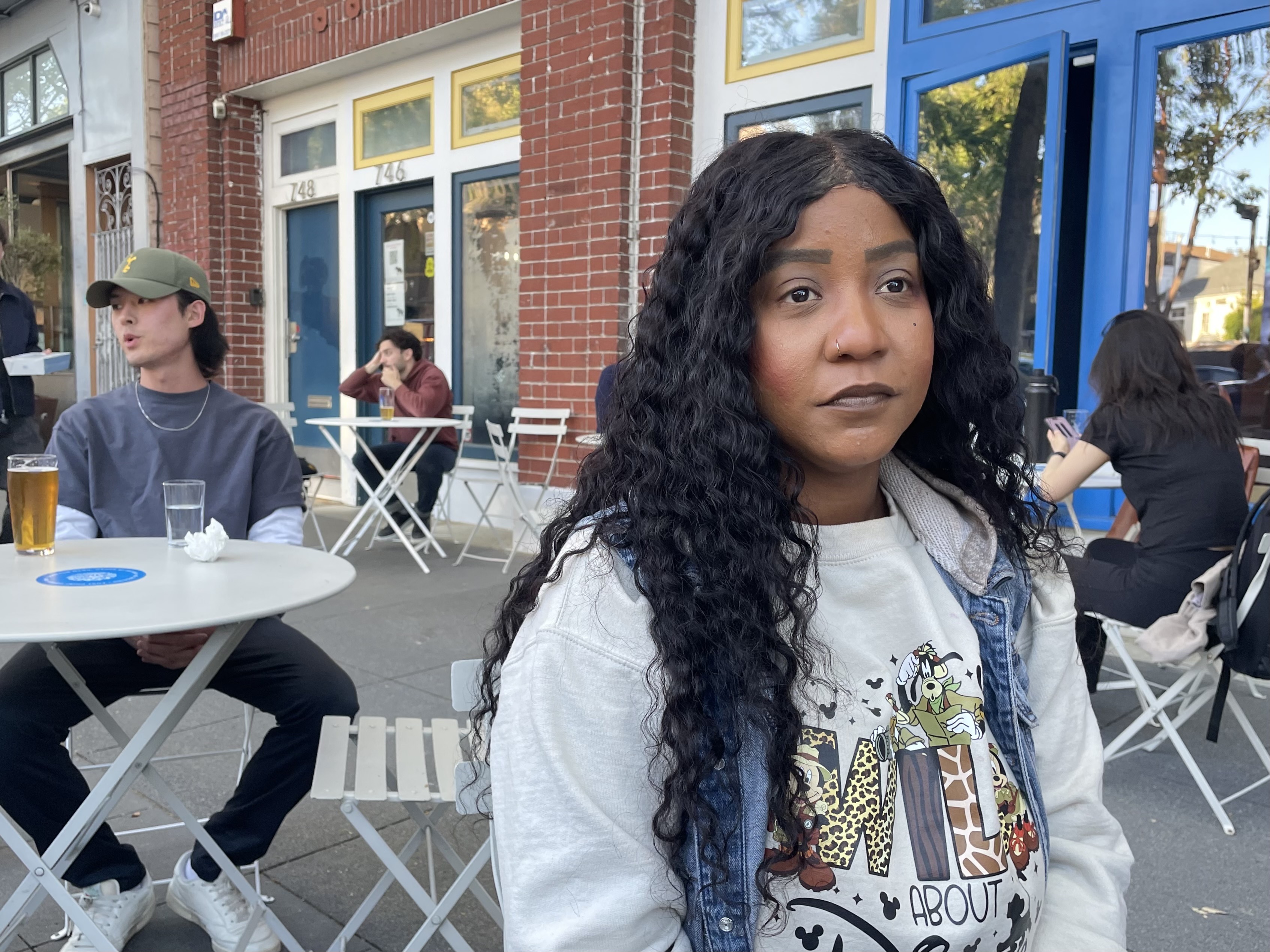 A woman sits at a restaurant outdoors.