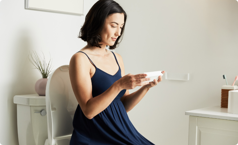 A woman sat on the bidetmega while using a smart device