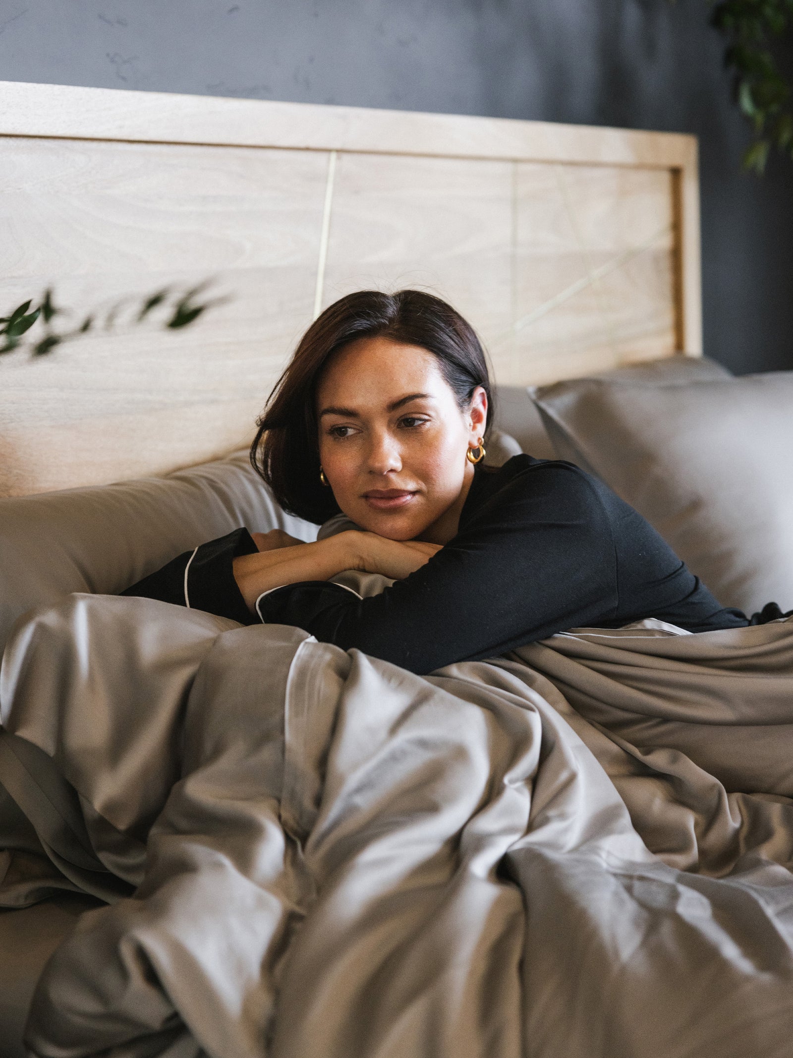 Woman lying in bed with dove grey bedding 