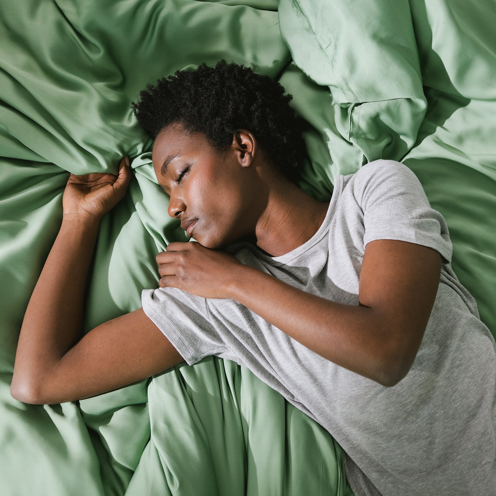 Fern Sheets on bed. A woman rests on the bed. 