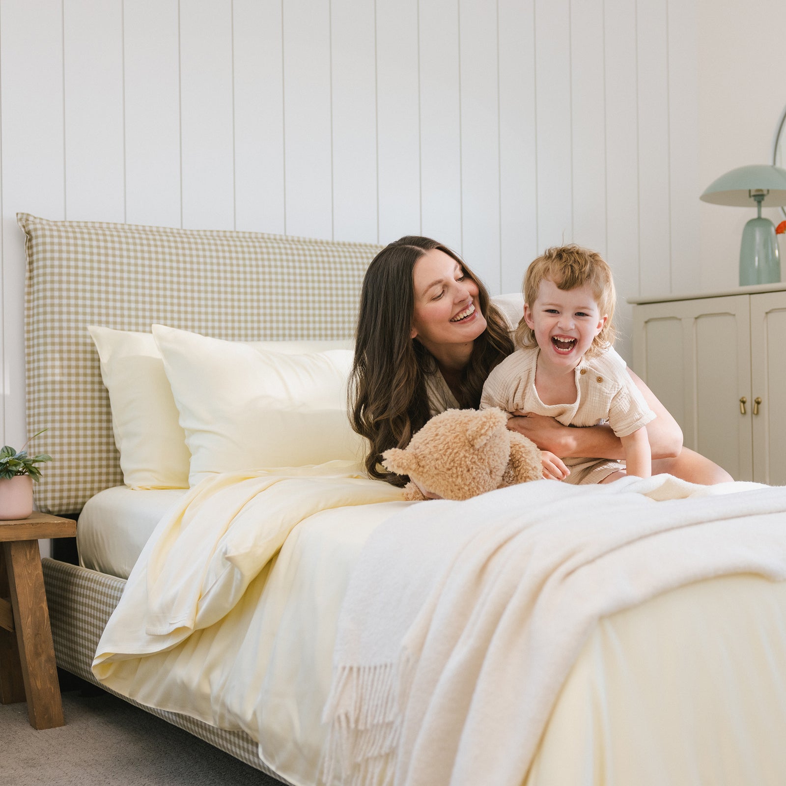 Lemonade Sheets on bed. A woman lays on the bed with her kid. 