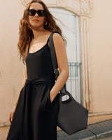 Woman wearing dress, sunglasses, and holding a handbag