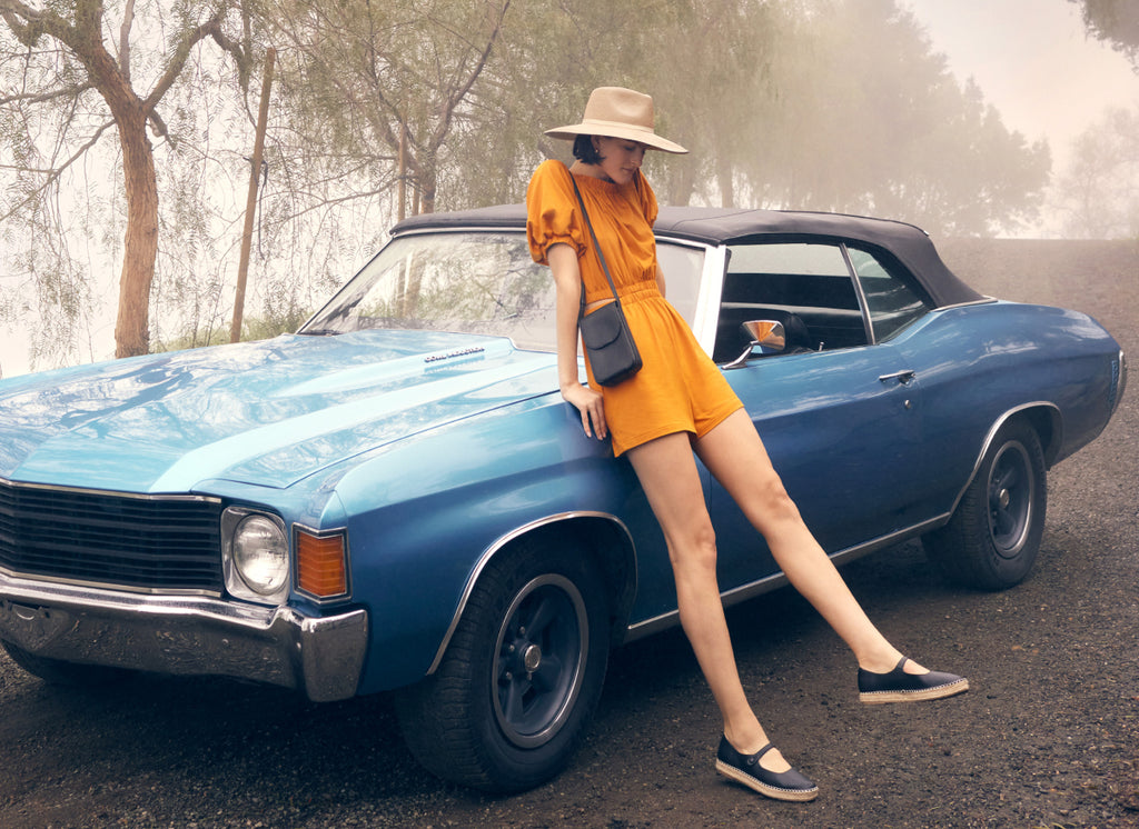 Woman standing next to a vintage car on a foggy road