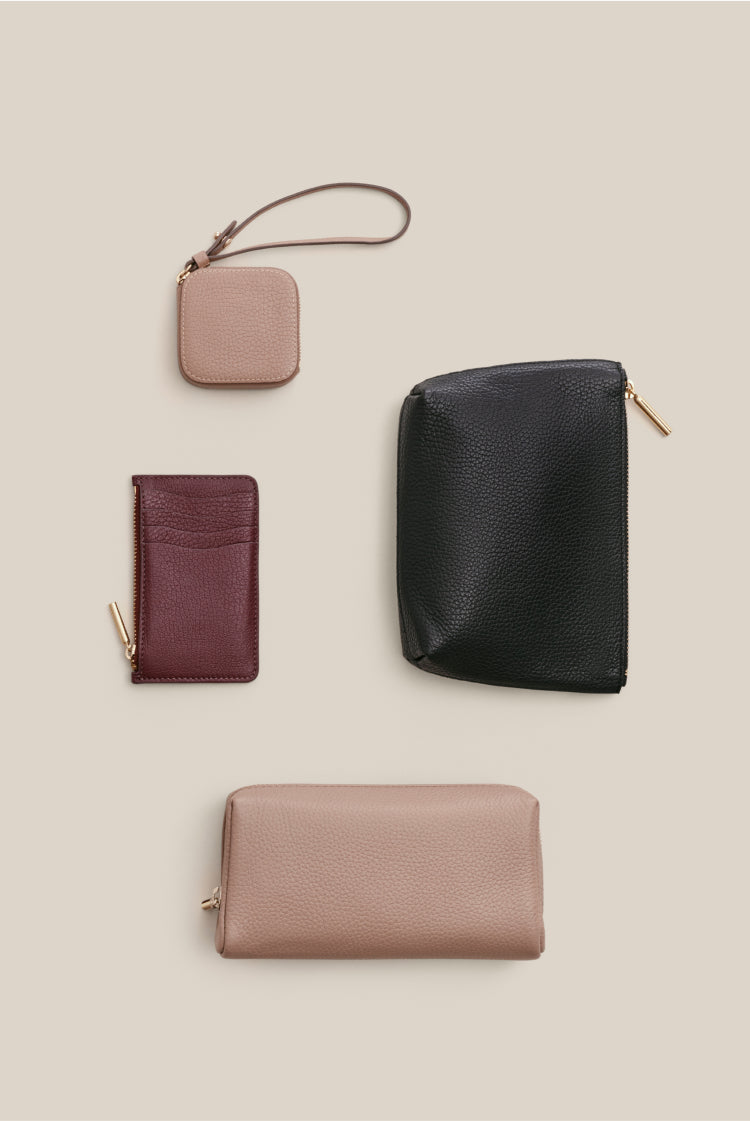 Four various wallets and a key holder arranged neatly on a plain background.