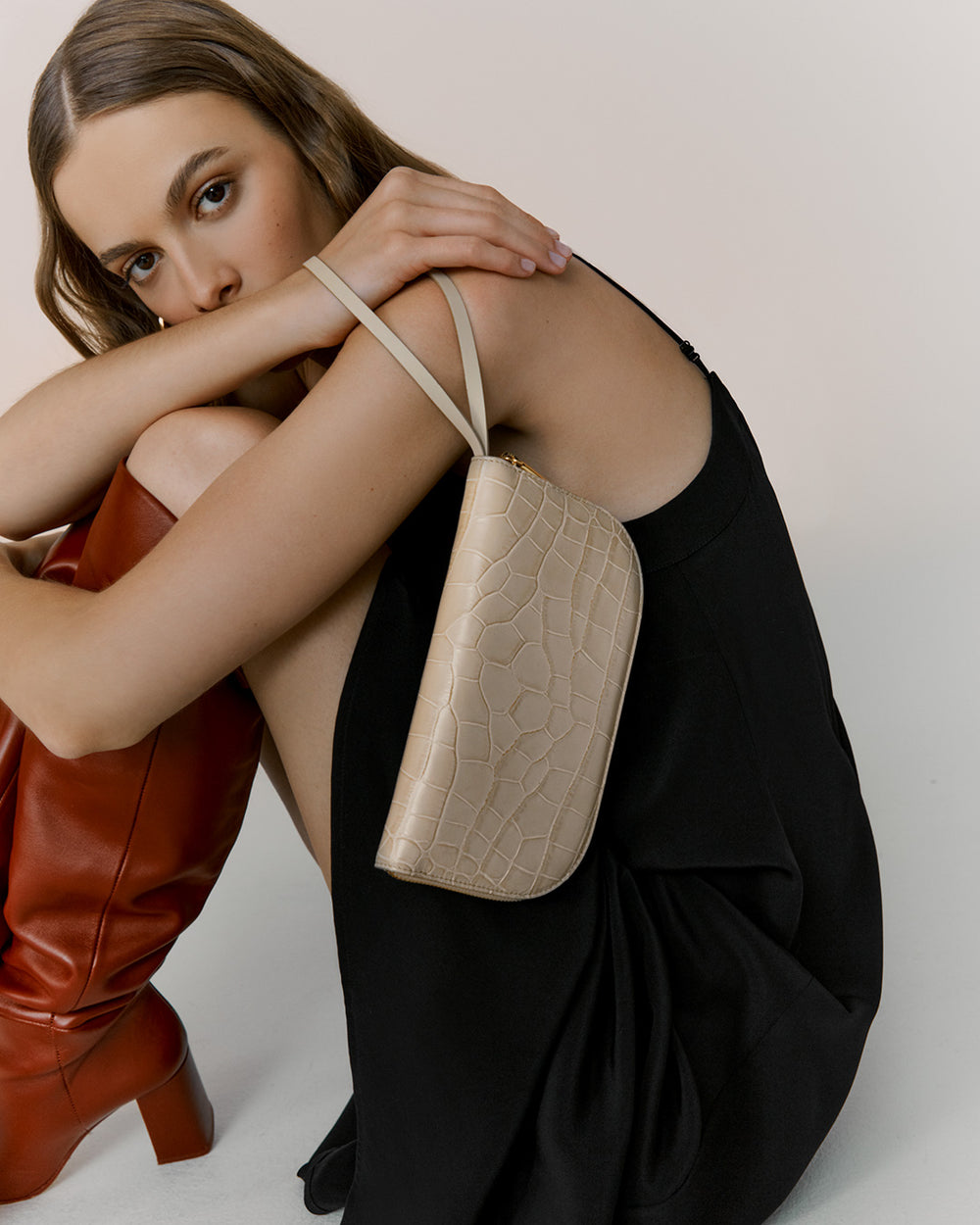 Woman sitting and holding a handbag.