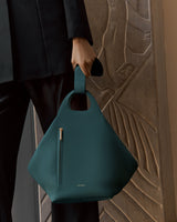 Person holding a structured handbag with a zipper pocket