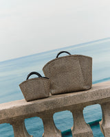 Two bags sitting on a seaside railing.