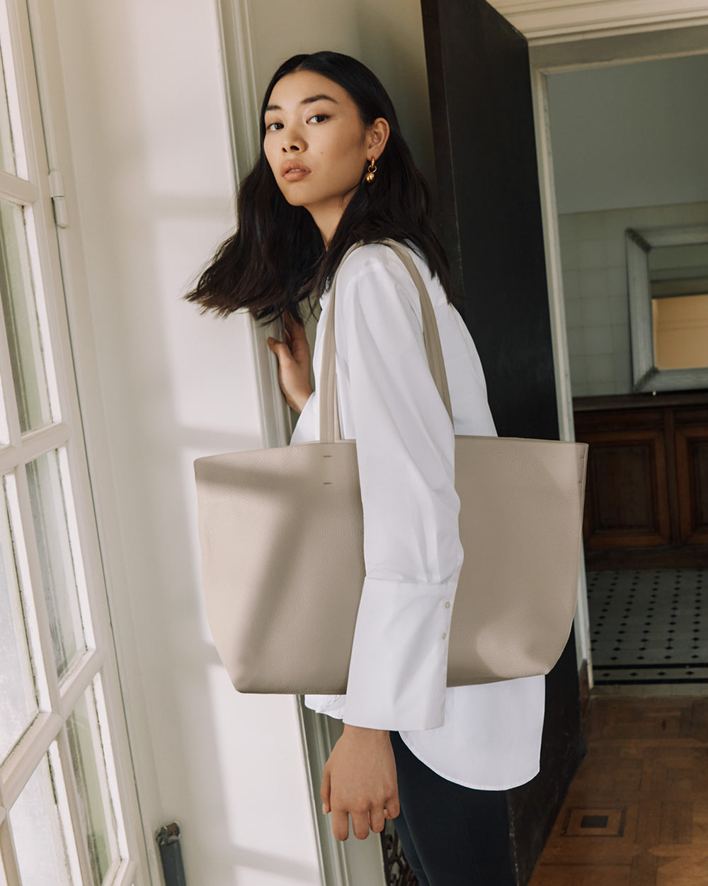 Woman holding a large bag standing by an open door.