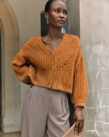 Woman leaning against a wall looking away from the camera.