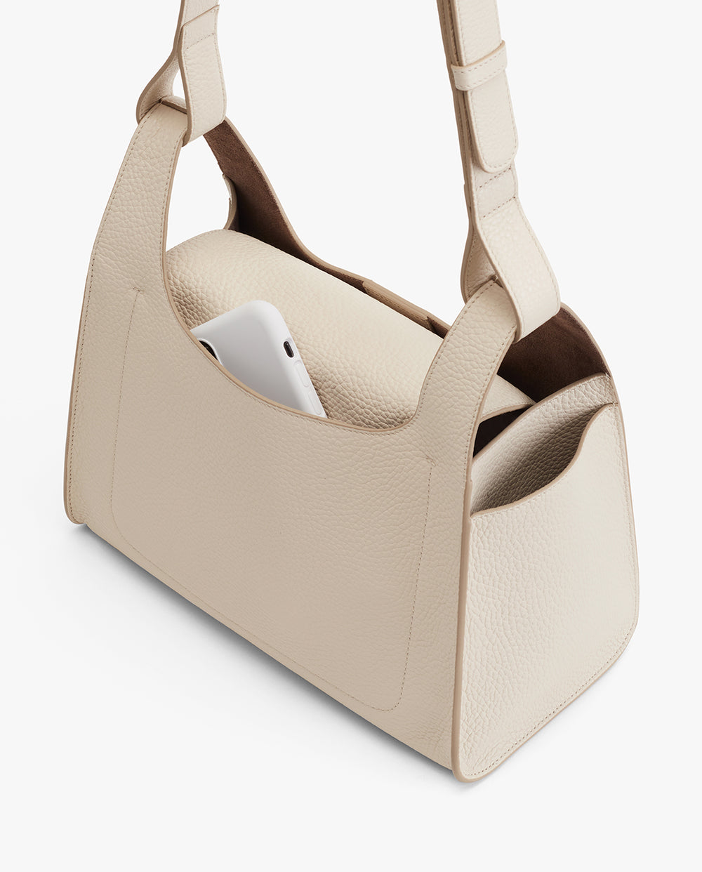 Handbag with a smartphone inside one of its pockets.