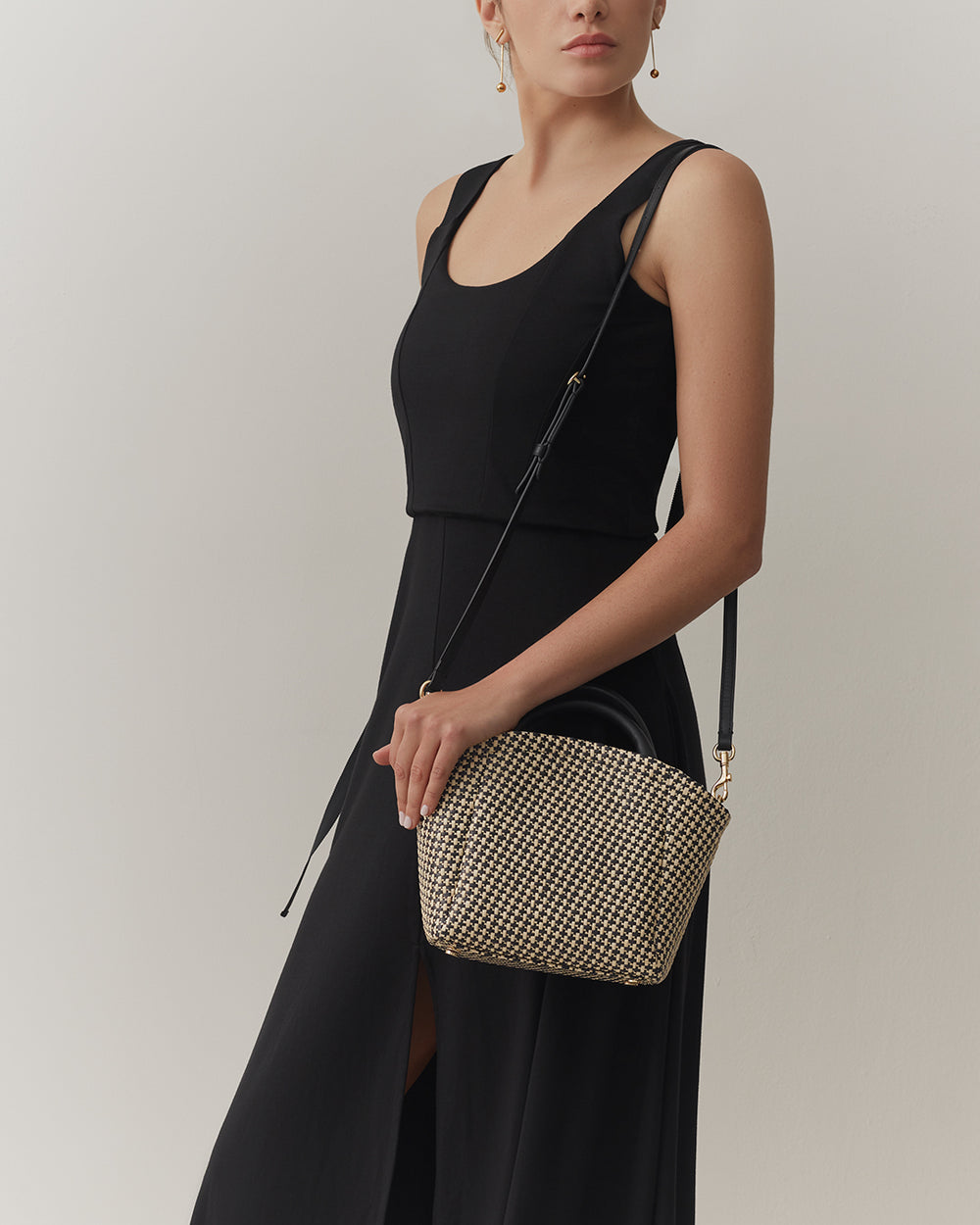 Woman in a sleeveless top holding a shoulder bag.