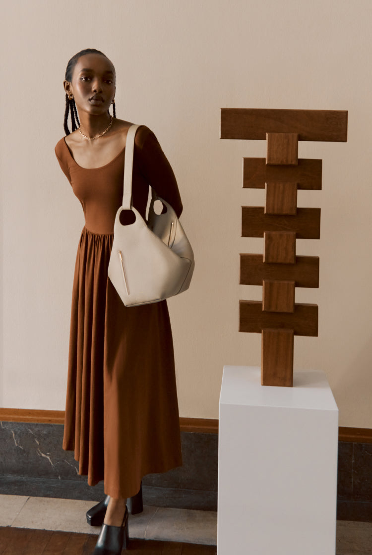 Woman standing next to a wooden sculpture on a pedestal.