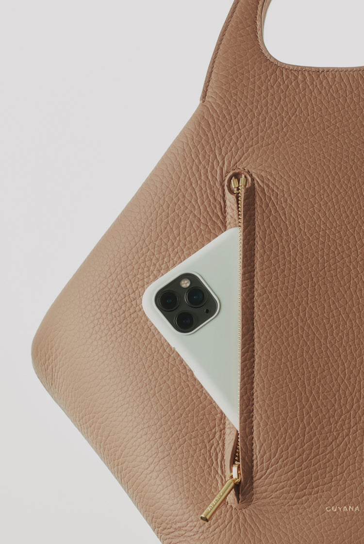 Smartphone in purse pocket with zipper detail.