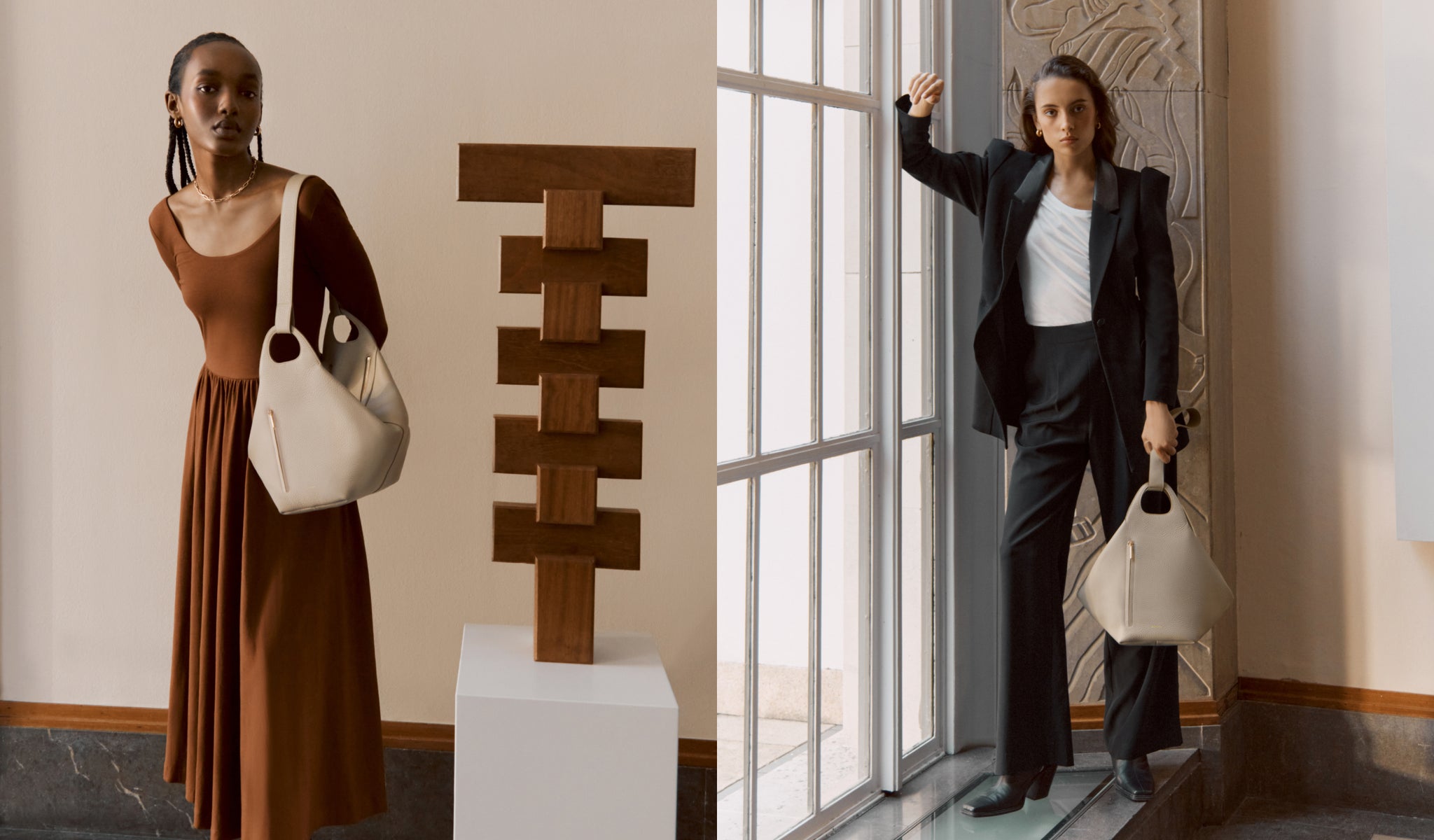 Two women standing next to a sculpture, each holding a bag.