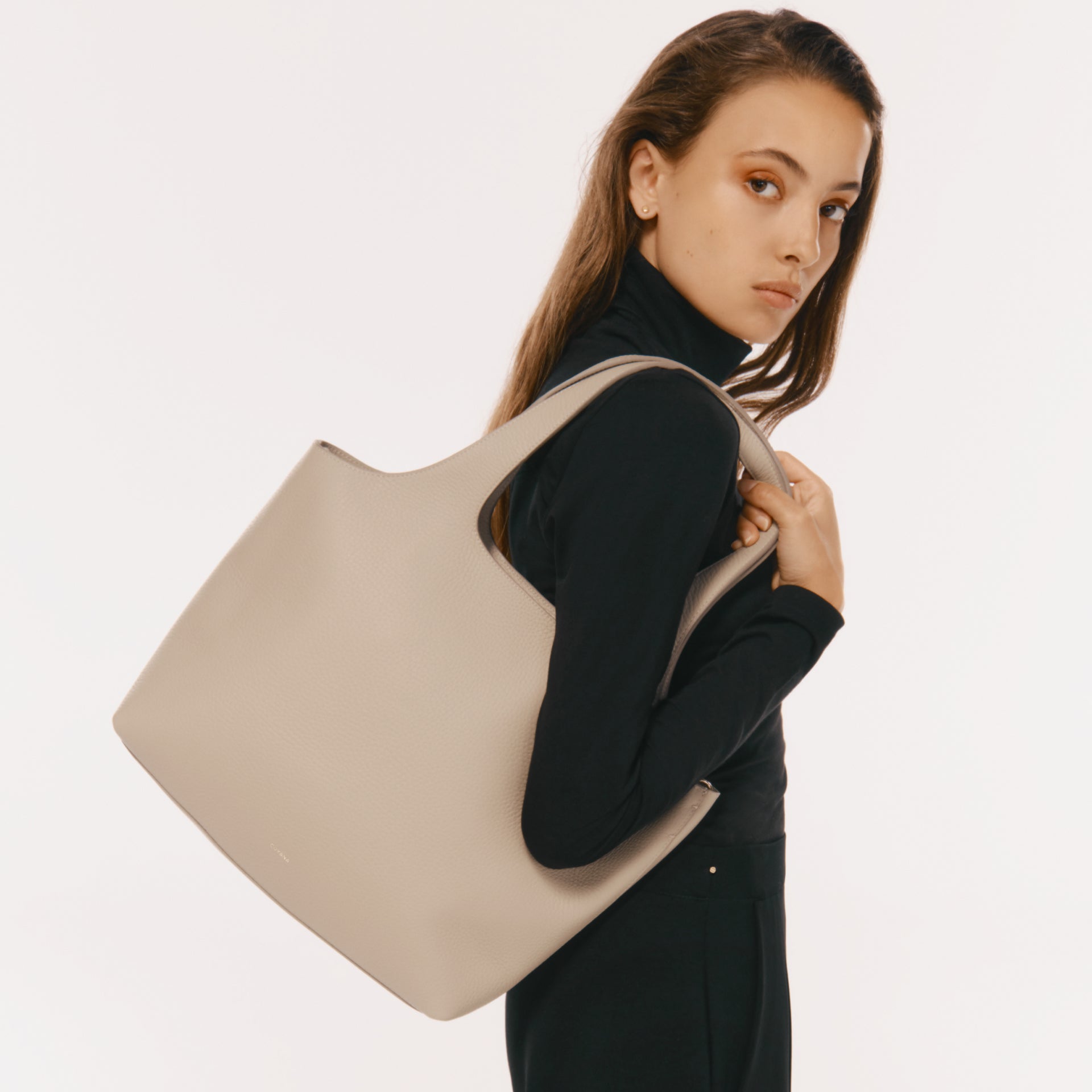 Woman looking over her shoulder holding a large bag.