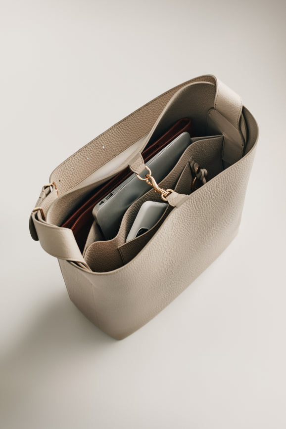 Open handbag with items inside on a surface.