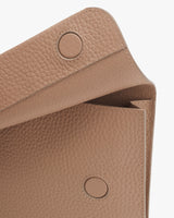 Close-up view of a textured handbag with flap closure and snap buttons.