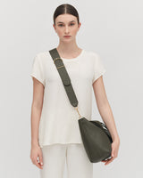 Woman standing with a shoulder bag.