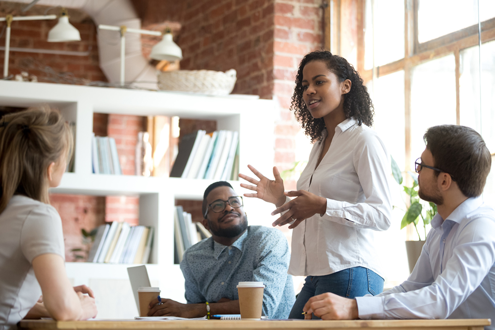 Ambitious african black female employee speaking at diverse meeting