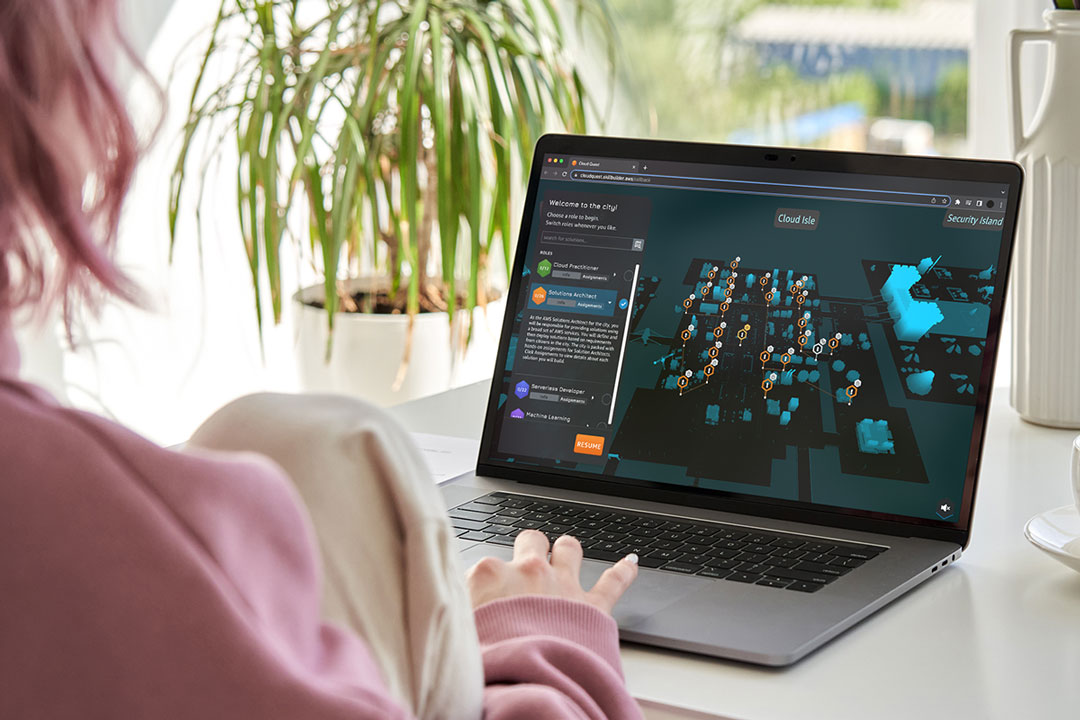 Một người tóc hồng và mặc áo len màu hồng đang chơi AWS Cloud Quest trên máy tính xách tay