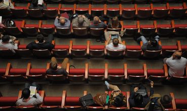 Pessoas sentadas em cadeiras de auditório.