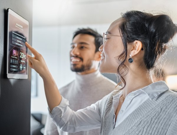 Image of a woman interacting with a screen on a wall in a home with a man standing next to her and smiling