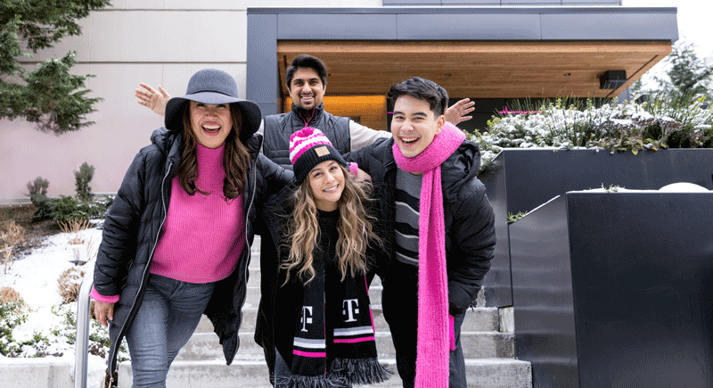 Four people in black and pink clothes smiling at the camera