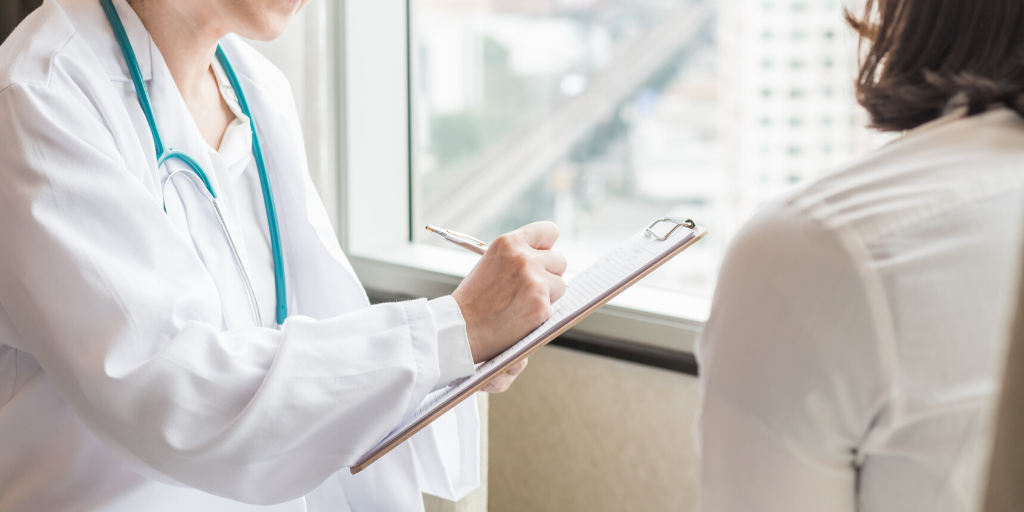 doctor filling out chart of female patient