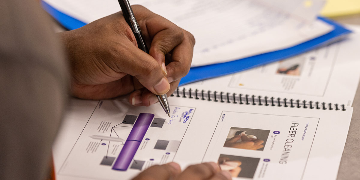 Pictured: Student writes in a notebook from the AWS Fiber Optic Splicing Course.