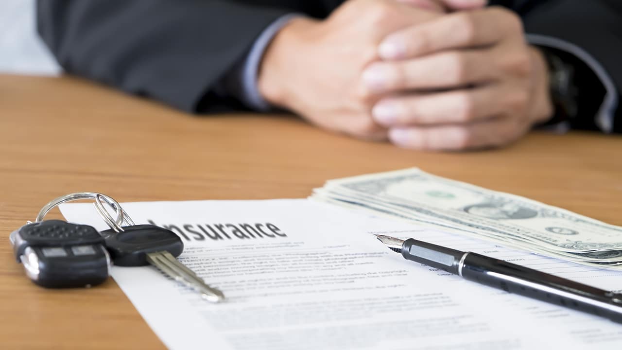 Closeup of a pen with car key, money to pay for car insurance.