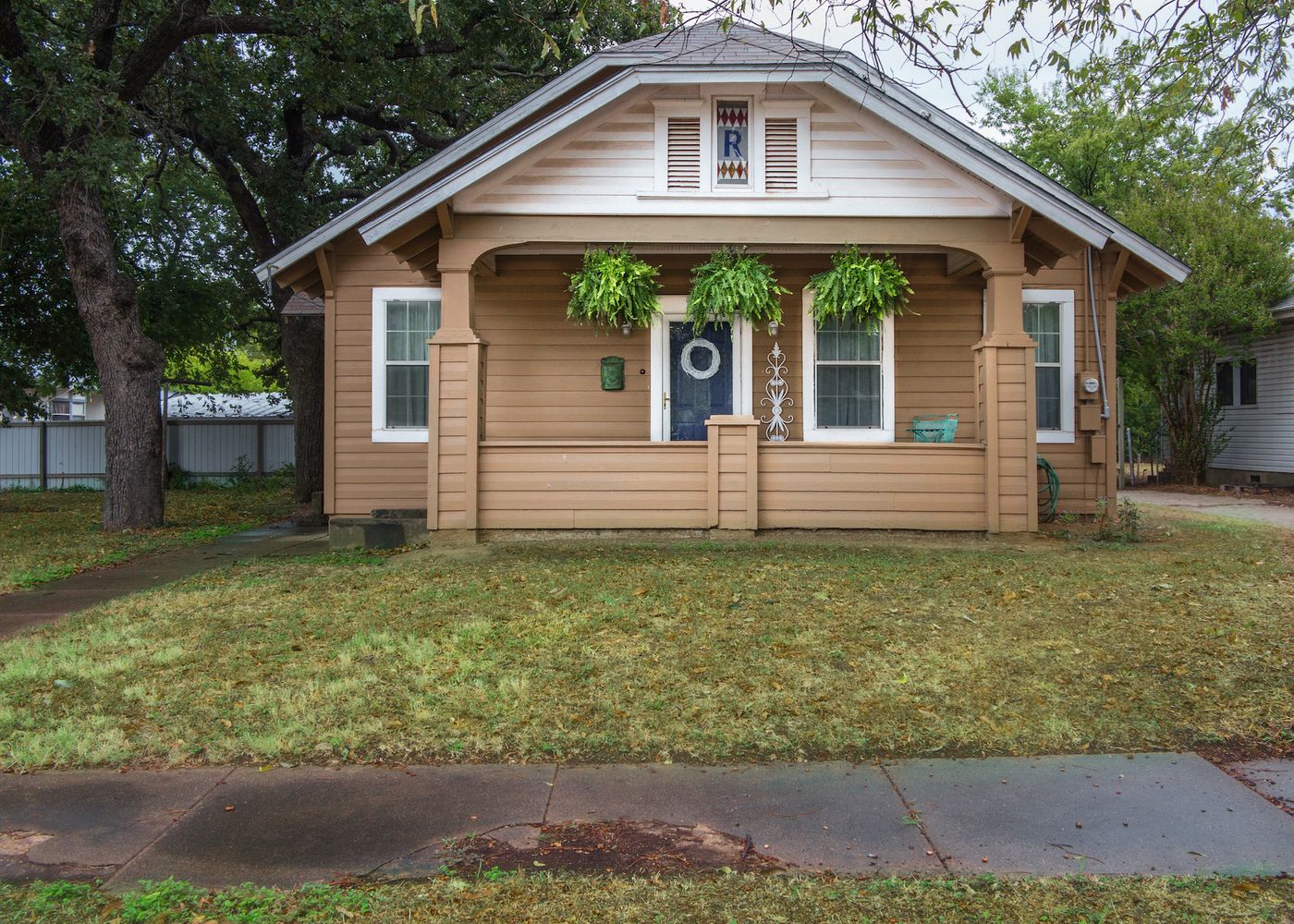 Brown house with blue door and green yard.