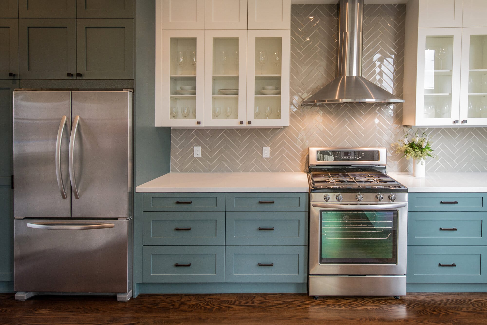 Kitchen with stainless steal refrigerator and stove with white cabinets and blue drawers