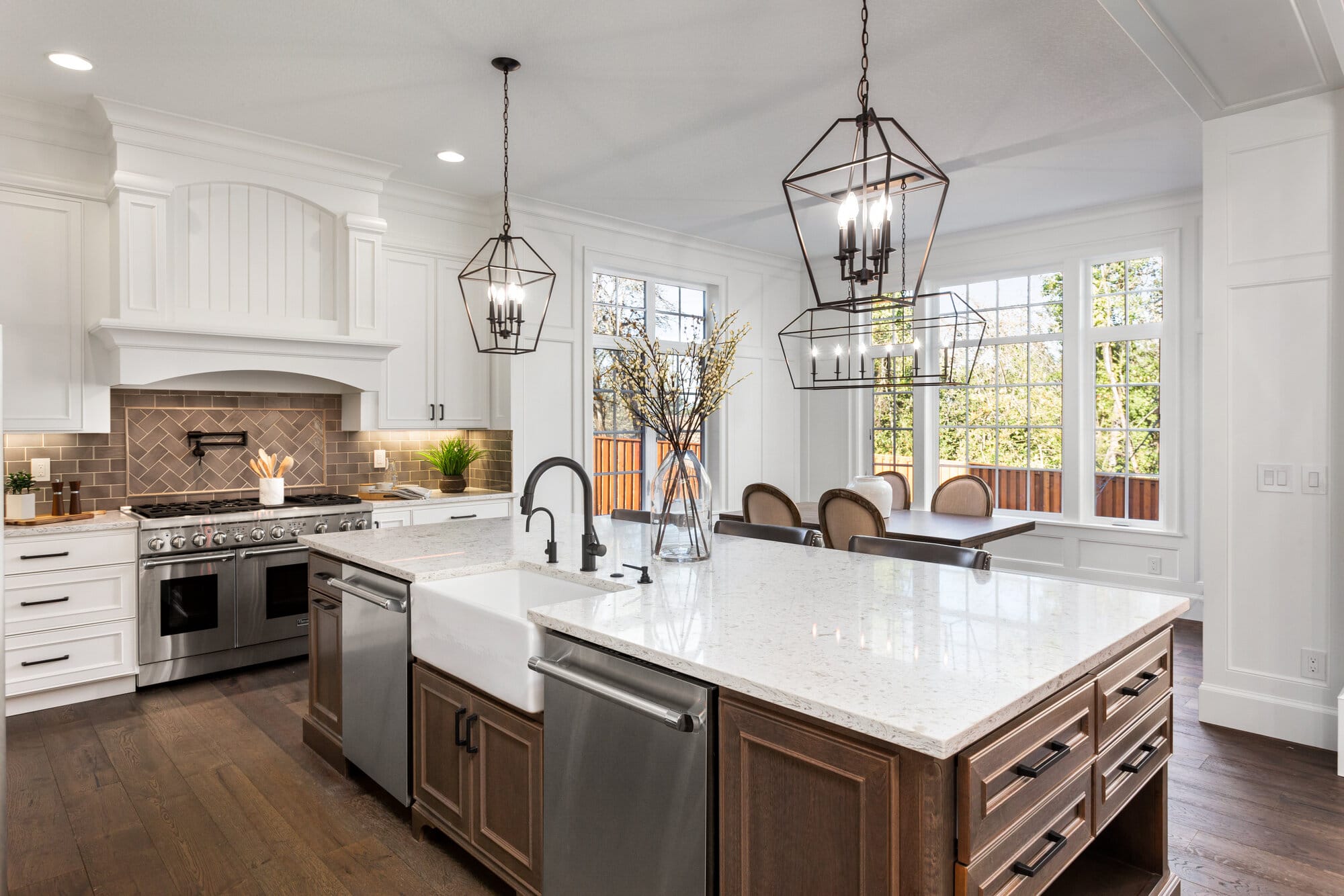 A kitchen with white countertop, stainless steel dishwasher, and iron light fixtures.