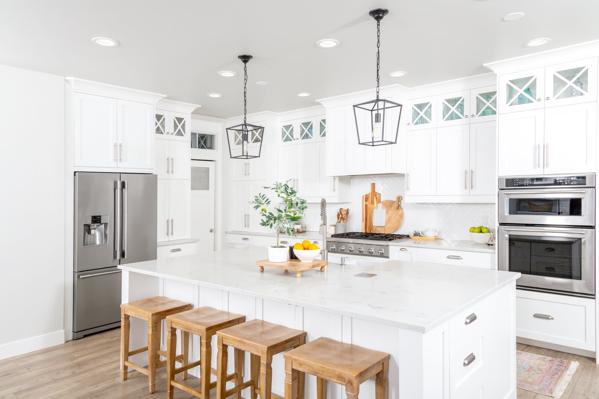 A white kitchen with stainless steal appliances and wooden stools