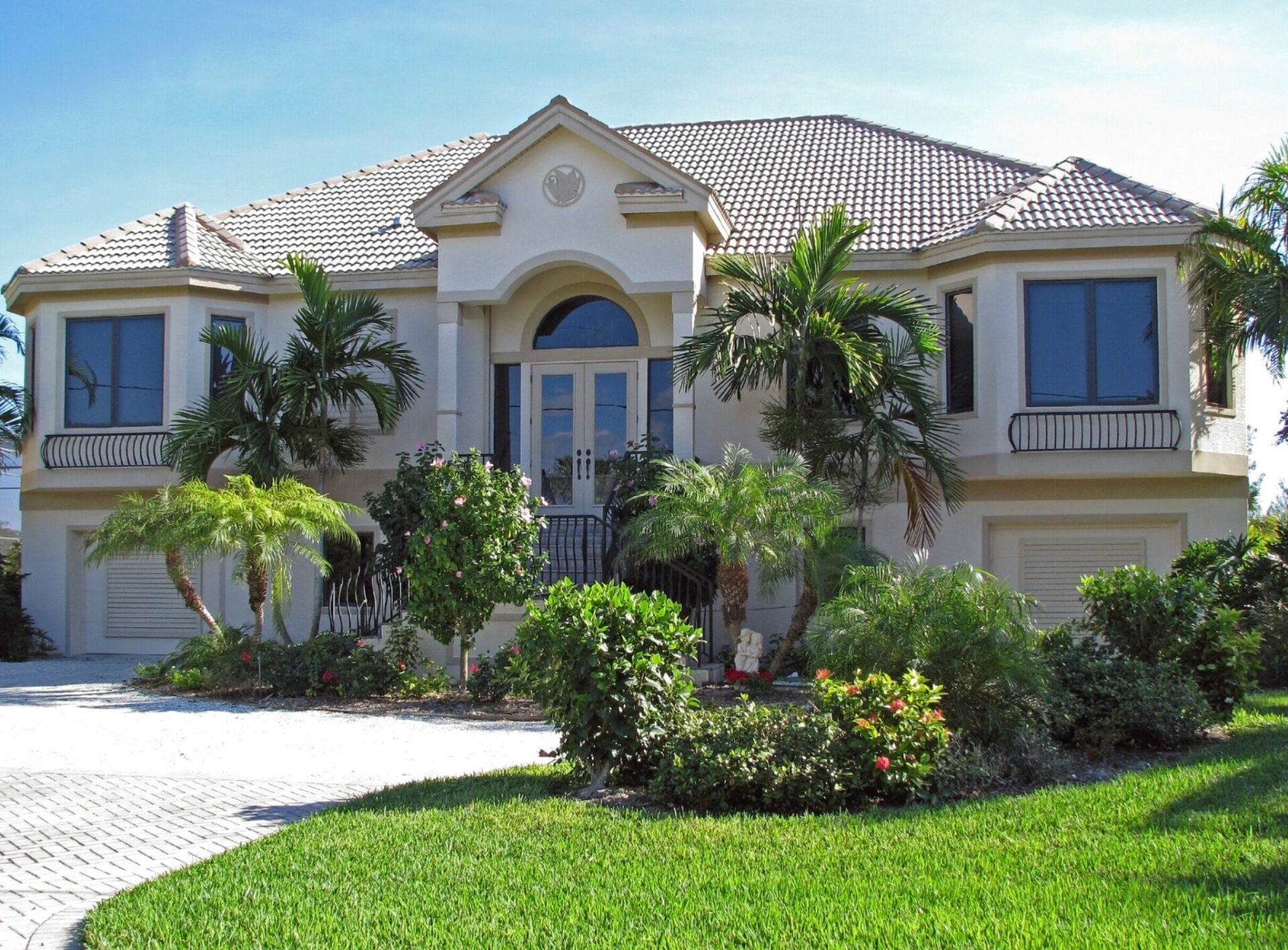 A home in Florida painted white with large green yard and palm trees.