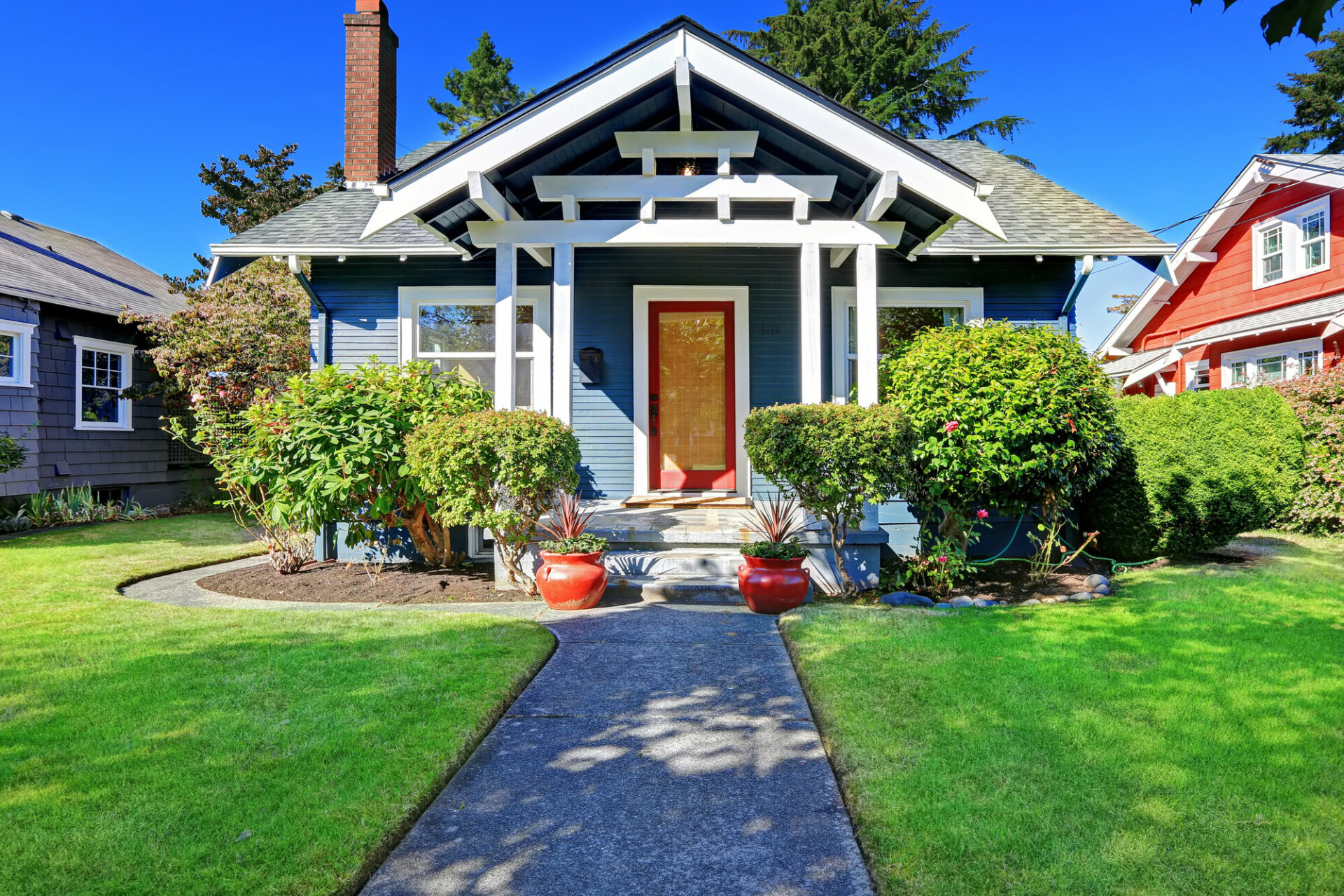 A navy blue craftsman home with red front door.