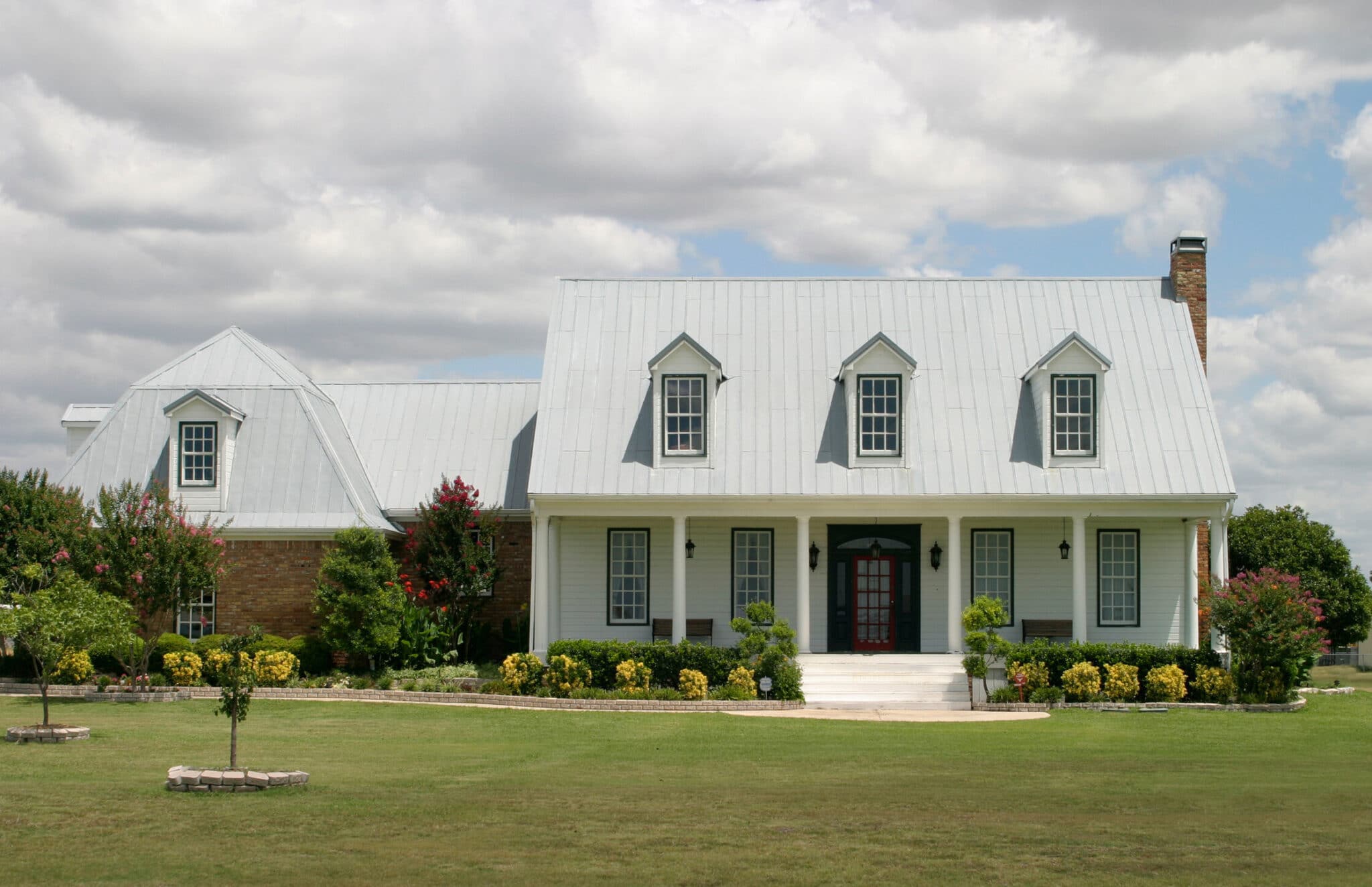 Updated white ranch house with large green lawn.